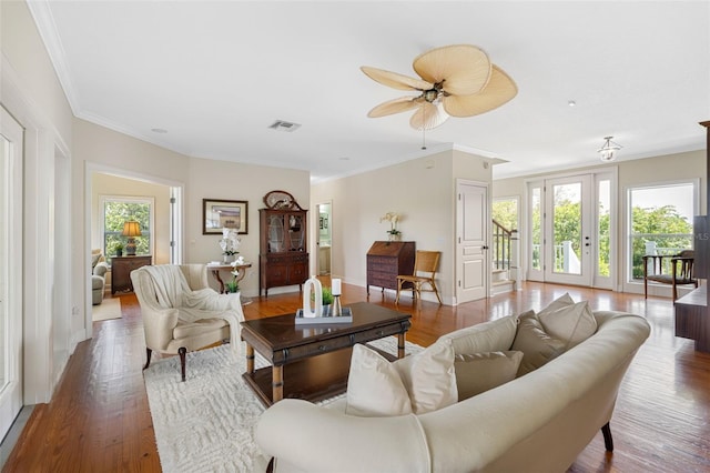 living area featuring ornamental molding, visible vents, ceiling fan, and wood finished floors