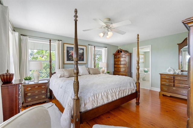 bedroom with ensuite bath, wood finished floors, a ceiling fan, and baseboards