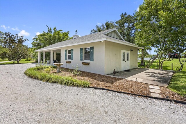 view of front of property featuring driveway, roof with shingles, and stucco siding