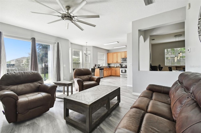 living room featuring a textured ceiling and ceiling fan with notable chandelier