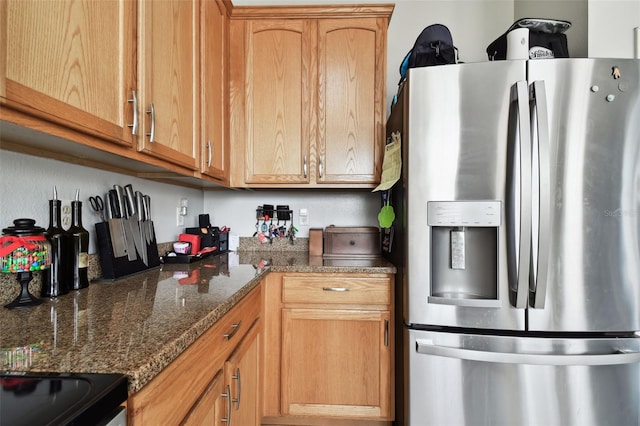 kitchen with dark stone countertops and stainless steel refrigerator with ice dispenser