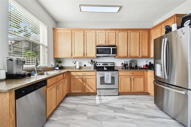 kitchen featuring dark stone counters, stainless steel appliances, a textured ceiling, and sink