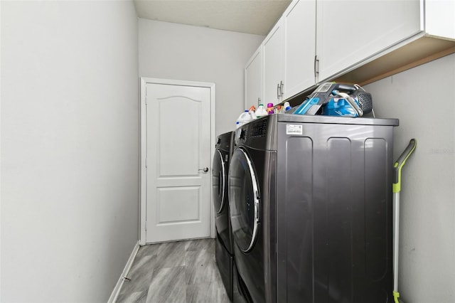 clothes washing area with cabinets, light hardwood / wood-style floors, and independent washer and dryer