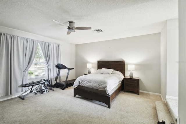 bedroom featuring ceiling fan, light colored carpet, and a textured ceiling