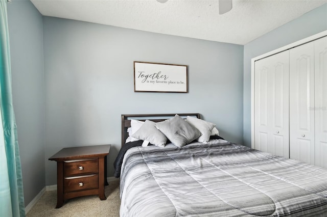 bedroom with ceiling fan, a textured ceiling, a closet, and light carpet