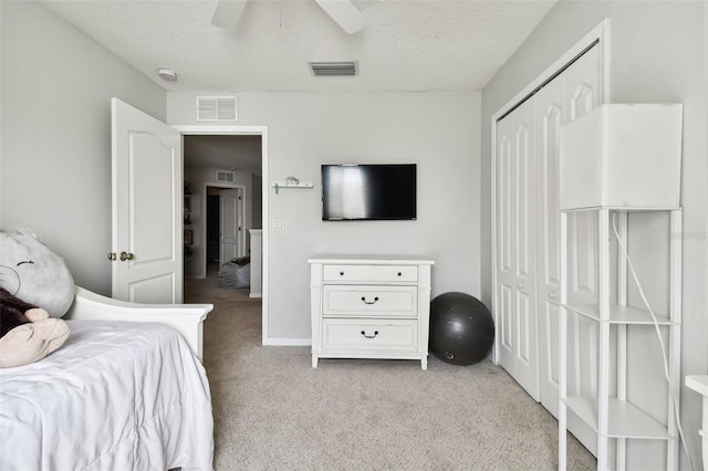 carpeted bedroom featuring ceiling fan, a textured ceiling, and a closet