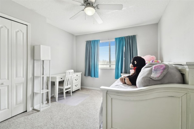 bedroom featuring ceiling fan, light colored carpet, a textured ceiling, and a closet