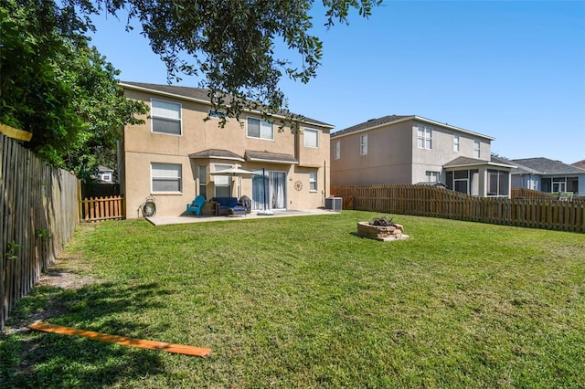 rear view of house with a lawn, a patio, central AC unit, and a fire pit