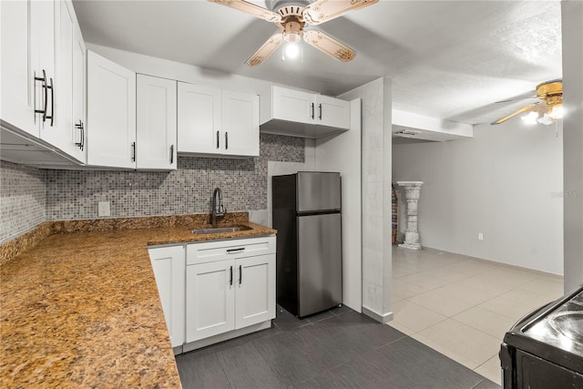 kitchen featuring ceiling fan, white cabinets, stainless steel fridge, sink, and backsplash