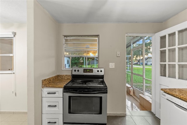 kitchen with light tile patterned flooring, white cabinetry, dishwasher, electric range, and dark stone counters