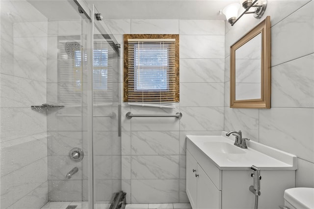 bathroom featuring tile walls, vanity, toilet, and an enclosed shower