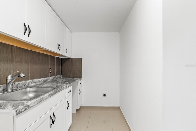 kitchen featuring white cabinets, light tile patterned floors, and sink