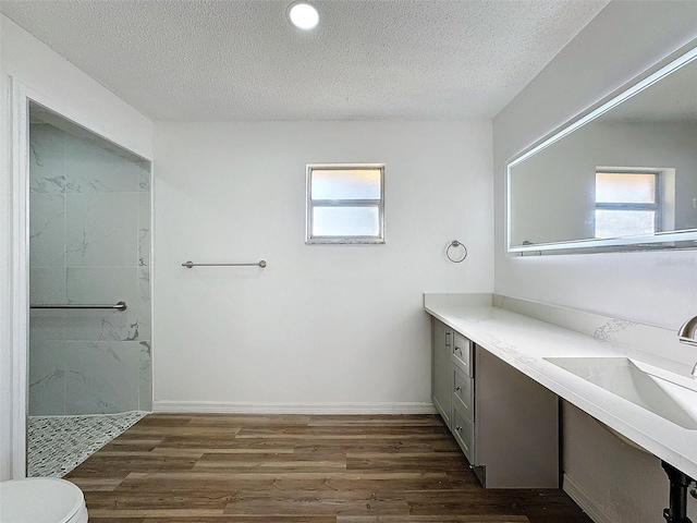 bathroom featuring plenty of natural light, a textured ceiling, wood finished floors, and a walk in shower