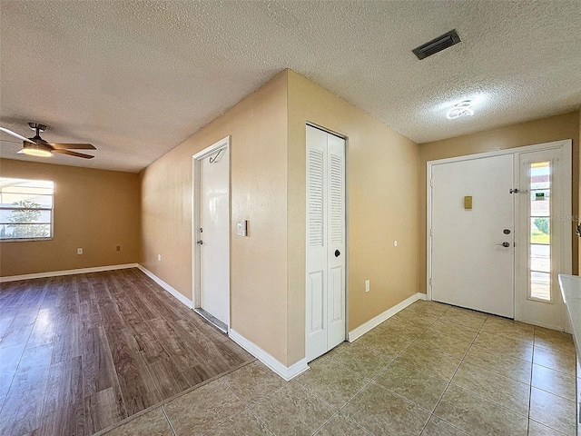 foyer entrance featuring visible vents, a ceiling fan, a textured ceiling, tile patterned flooring, and baseboards