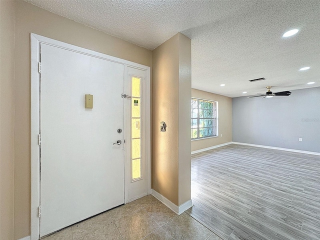 foyer entrance with visible vents, light wood-type flooring, a textured ceiling, recessed lighting, and baseboards