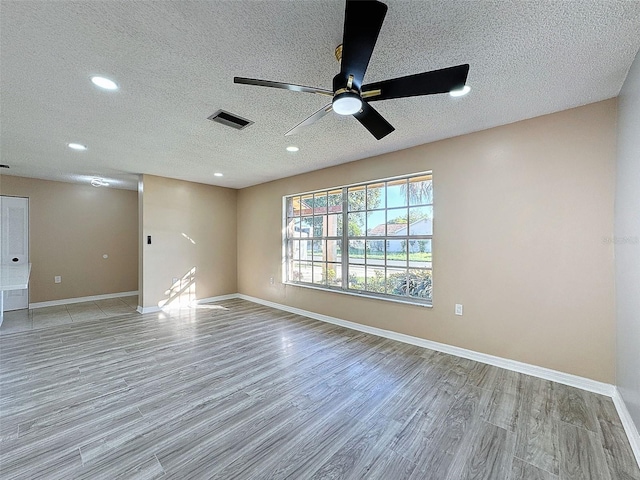 spare room with visible vents, a textured ceiling, recessed lighting, light wood finished floors, and baseboards