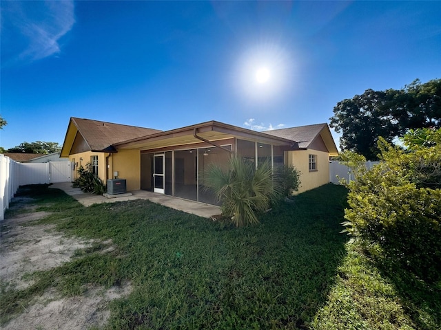 back of house with stucco siding, a fenced backyard, a yard, a sunroom, and central AC unit