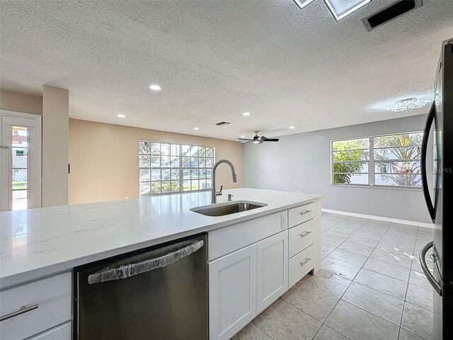 kitchen featuring stainless steel dishwasher, a wealth of natural light, freestanding refrigerator, and a sink