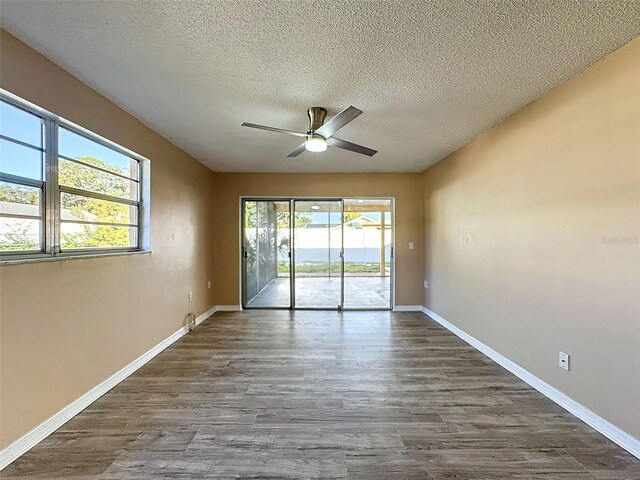 spare room featuring dark wood-type flooring, a ceiling fan, baseboards, and a textured ceiling