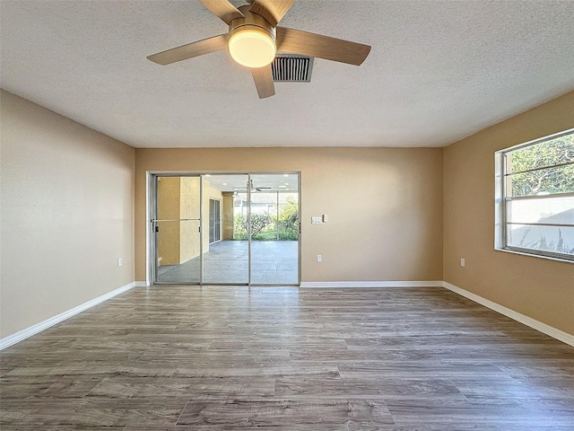 spare room with visible vents, baseboards, wood finished floors, and a textured ceiling