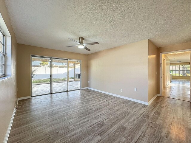 unfurnished room with a textured ceiling, wood finished floors, baseboards, and ceiling fan