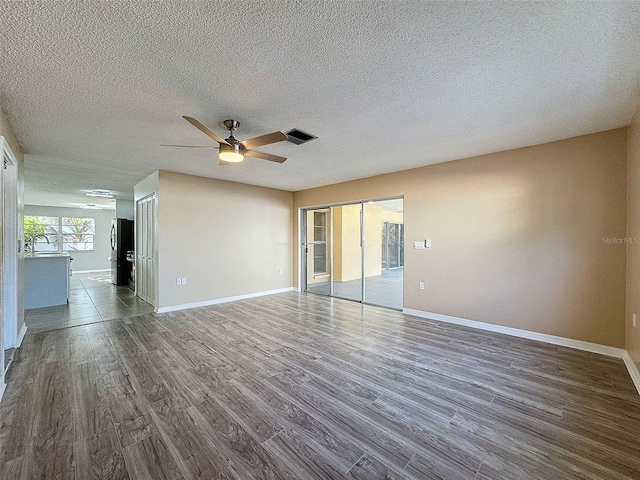 unfurnished living room with dark wood-type flooring, visible vents, ceiling fan, and a sink
