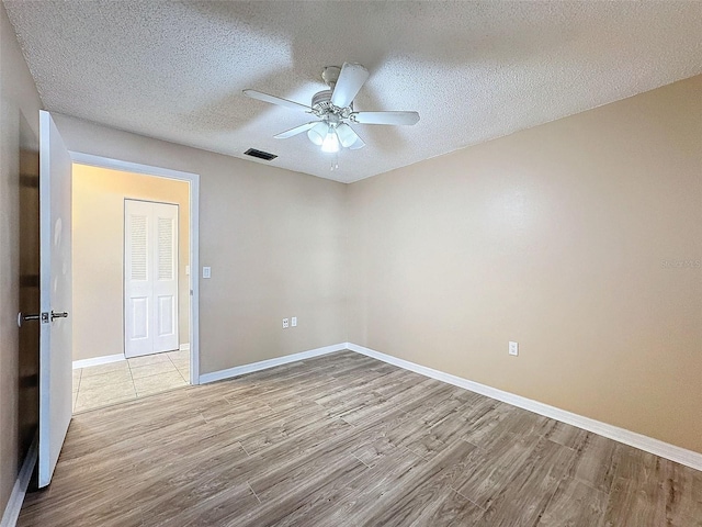 empty room with visible vents, baseboards, ceiling fan, a textured ceiling, and wood finished floors