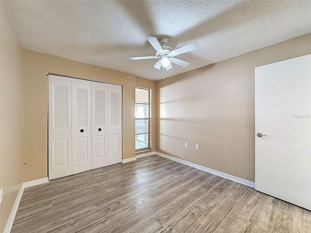 unfurnished bedroom featuring a textured ceiling, wood finished floors, and baseboards