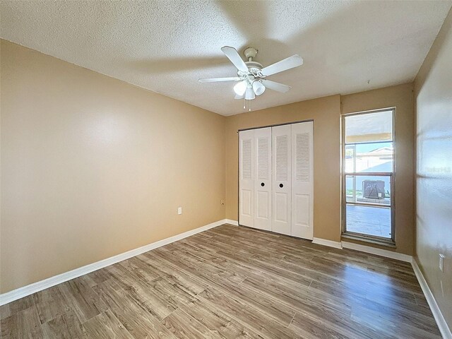 unfurnished bedroom featuring baseboards, a textured ceiling, and wood finished floors