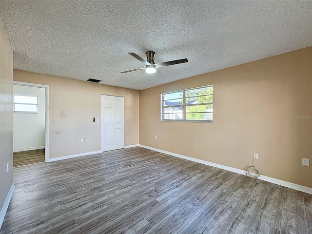 unfurnished bedroom with baseboards, a textured ceiling, and dark wood finished floors