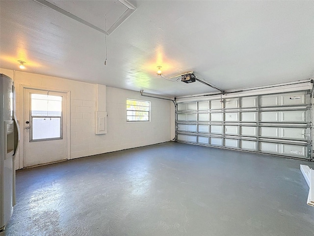 garage with a garage door opener and stainless steel fridge