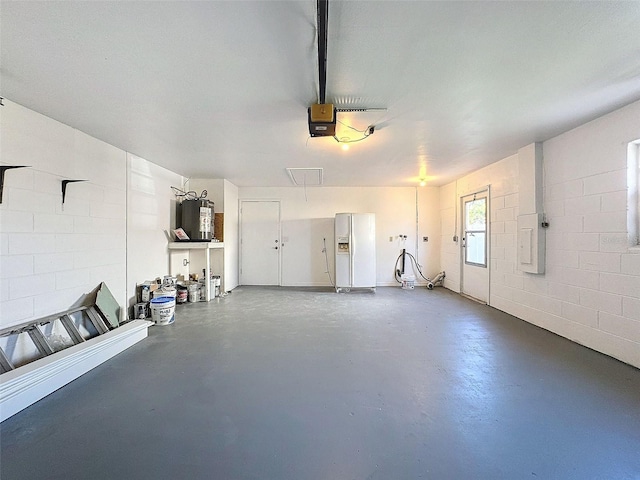 garage with water heater, white refrigerator with ice dispenser, a garage door opener, and concrete block wall