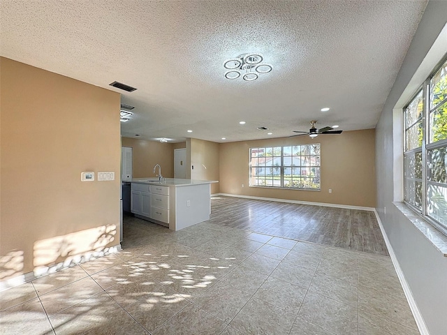 interior space with light tile patterned floors, baseboards, visible vents, a sink, and a textured ceiling