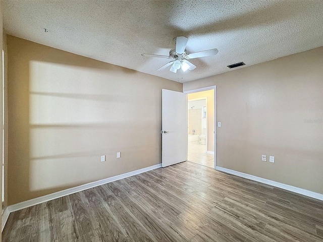 spare room with visible vents, baseboards, a textured ceiling, and wood finished floors