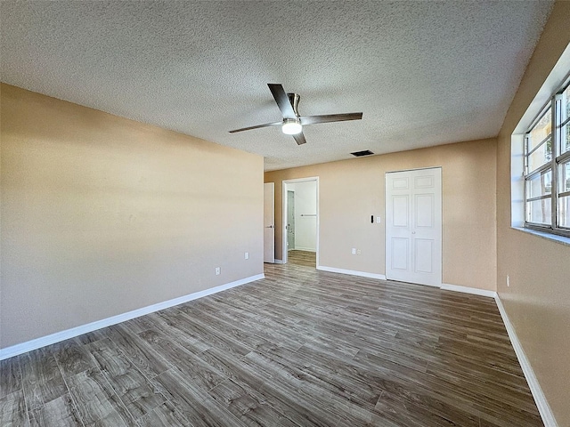 unfurnished bedroom featuring baseboards, visible vents, dark wood-style flooring, and a textured ceiling