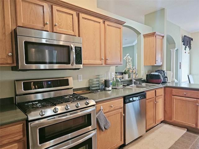 kitchen featuring ornate columns, appliances with stainless steel finishes, sink, and crown molding