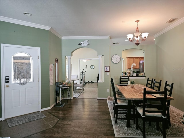 dining area with a chandelier, wood-type flooring, ornate columns, and ornamental molding