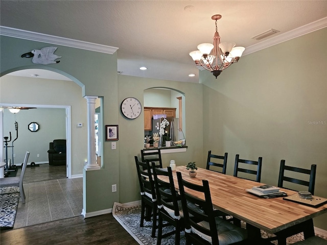 dining area with dark wood-type flooring, decorative columns, a notable chandelier, and crown molding