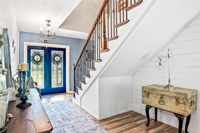 entryway featuring a chandelier, french doors, stairway, and wood finished floors