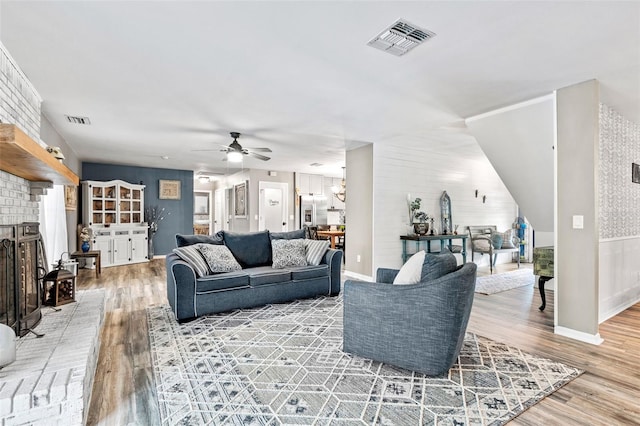 living room featuring light hardwood / wood-style flooring, ceiling fan, and a fireplace