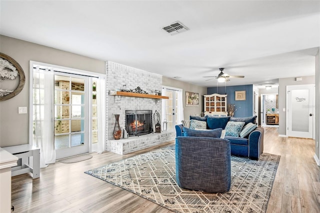 living room with ceiling fan, a fireplace, wood-type flooring, and a healthy amount of sunlight