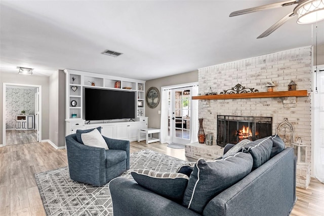 living room with light hardwood / wood-style flooring, french doors, built in shelves, a brick fireplace, and ceiling fan