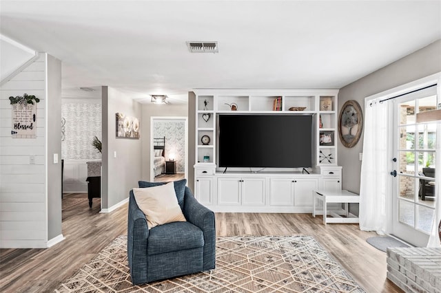 living area featuring visible vents, light wood-style flooring, and baseboards