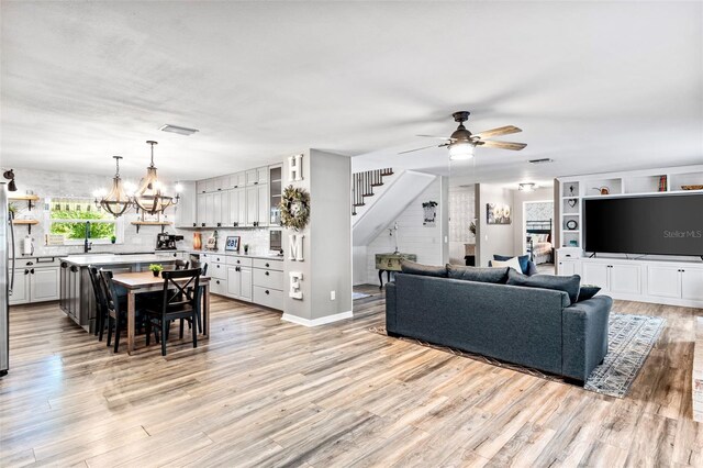 living room featuring ceiling fan with notable chandelier and light hardwood / wood-style floors