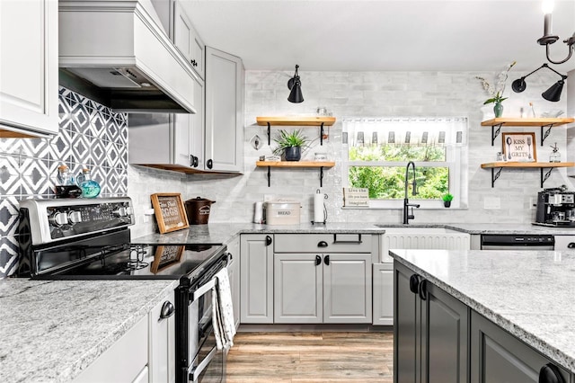 kitchen featuring open shelves, tasteful backsplash, custom range hood, stainless steel range with electric cooktop, and a sink