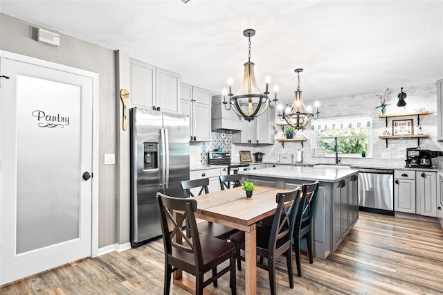 kitchen featuring a center island, light hardwood / wood-style flooring, stainless steel appliances, a chandelier, and sink