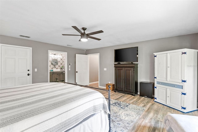 bedroom with ceiling fan, radiator, connected bathroom, and light hardwood / wood-style floors