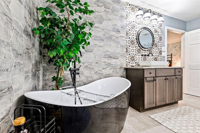 bathroom with tile patterned floors, a tub, vanity, and tile walls