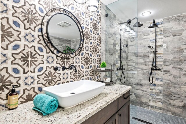 bathroom with vanity, tile walls, and a tile shower