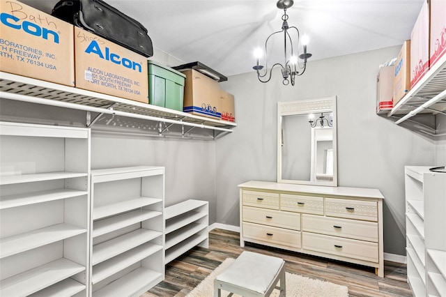 walk in closet with dark hardwood / wood-style flooring and an inviting chandelier